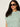 A woman with curly dark hair wears sunglasses and the Sanctuary Clothing perfect textured tee in chalk green juice stripe extended sizing, standing against a plain light background.
