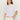 A woman with long brown hair wears the Sanctuary Clothing pleat bubble tee in white and high-waisted white pants, standing against a plain light background with one hand in her pocket.
