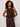 A woman with curly hair wears the Sanctuary Clothing retreat bubble tank in rich soil, a sleeveless, loose-fitting dark brown top, standing against a plain light background with her hands relaxed at her sides.