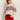 A woman models the Sanctuary Clothing send it sweater chalk multi€�featuring red and black geometric patterns€�with red pants and sunglasses, standing against a plain light background with one hand in her pocket.