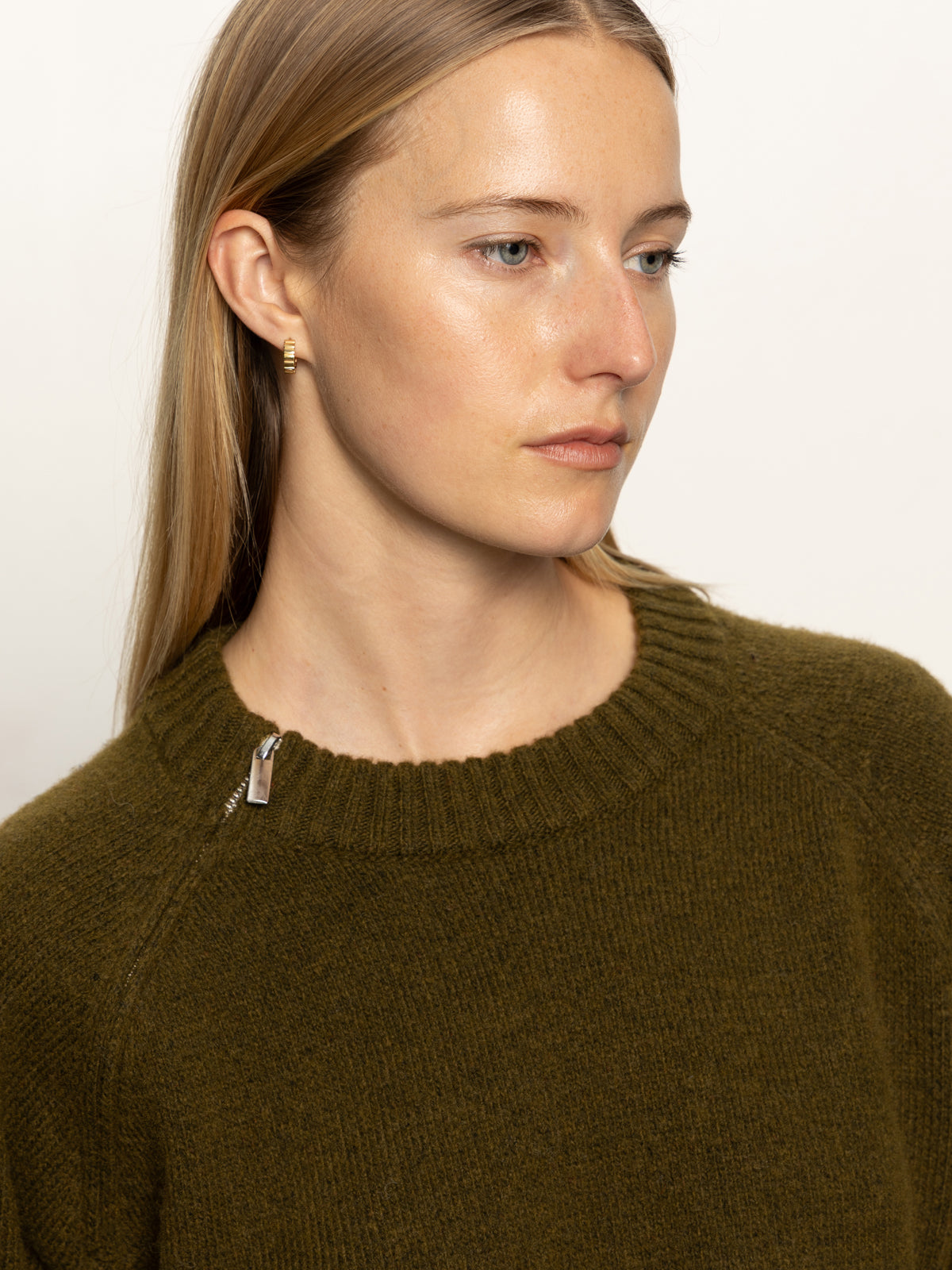 A woman with straight blonde hair wears the Sanctuary Clothing zip it sweater dirty martini, featuring a zip collar, against a plain background with a neutral expression.