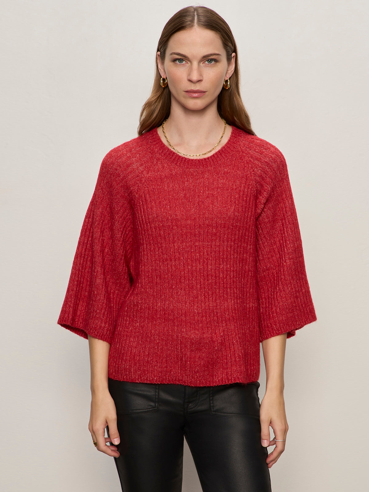 A person with long hair wears the Sanctuary Clothing ribbed sweater tee in cherry lacquer and black pants, standing against a plain light background.