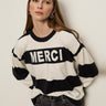 A woman with long brown hair wears Sanctuary Clothing„¢s 24 7 Popover Black with Chalk Stripe sweater. She stands against a light background, looking to the side with a neutral expression.