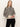 A woman with long, straight blonde hair wears the Sanctuary Clothing "soft touch popover spots" sweater�beige with black leopard print�and black pants, standing against a plain light background with a neutral expression.