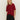 A woman with straight blonde hair wears the Sanctuary Clothing short sleeve shine sweater tee in cherry lacquer shine and black pants, standing against a plain light background with her hands in her pockets.