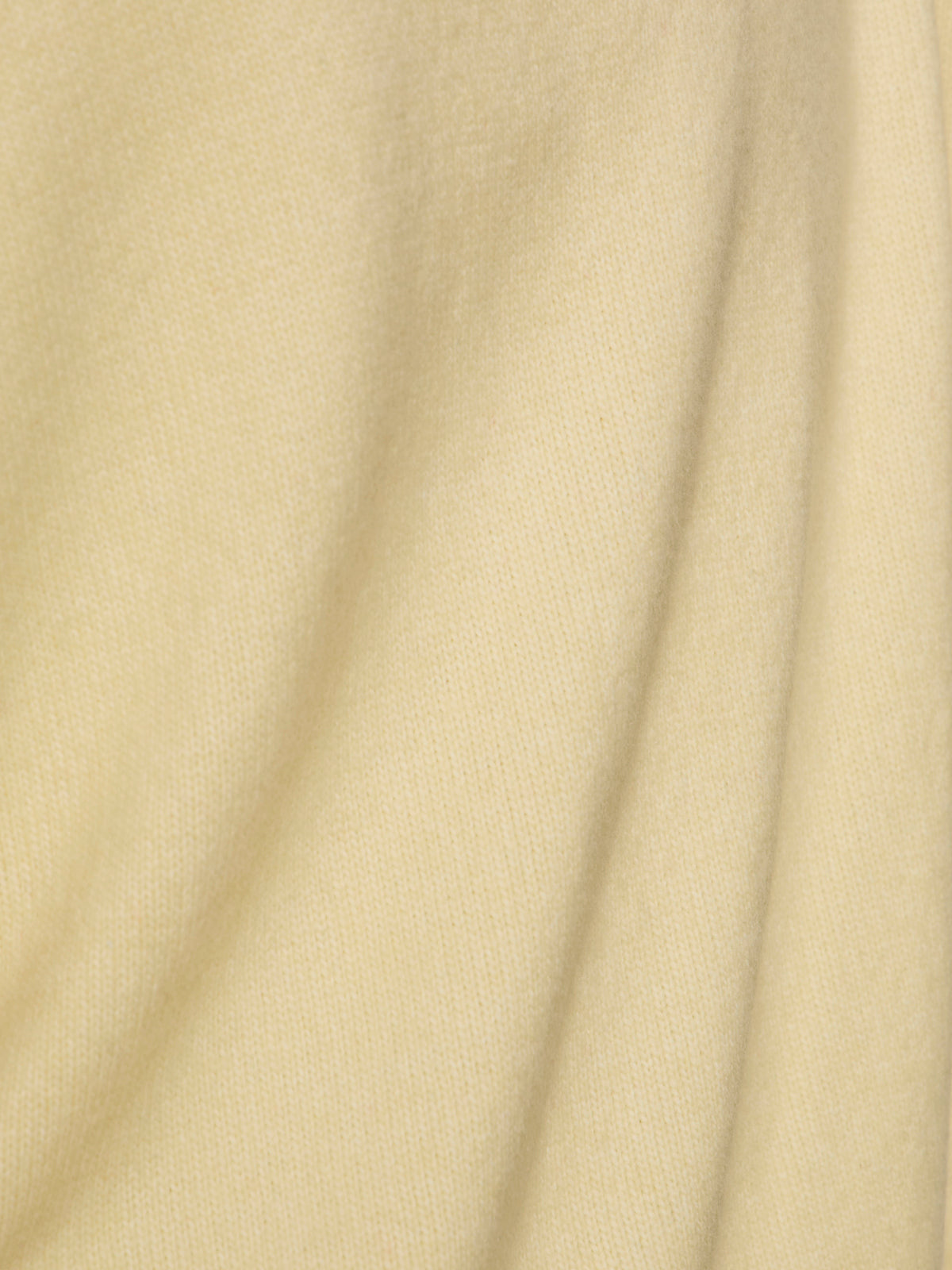 Close-up of the easy layering shell in buttercream by Sanctuary Clothing, featuring soft, light yellow fabric with subtle folds and a smooth, textured surface. Gentle curves create shadows that add depth to this versatile piece.