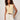 A woman with curly hair wears the Sanctuary Clothing manhattan rib button cardi in banana, paired with white shorts and a brown belt, standing against a light wall and looking at the camera with a relaxed expression.