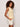 Woman with curly hair wears the Sanctuary Clothing manhattan rib button cardi banana, a sleeveless light yellow top, paired with white shorts. She stands sideways with one hand in her pocket against a plain light background.