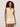 A woman with curly hair wears the Sanctuary Clothing manhattan rib button cardi in banana and off-white shorts, standing against a plain light background with one arm relaxed and the other in her pocket.