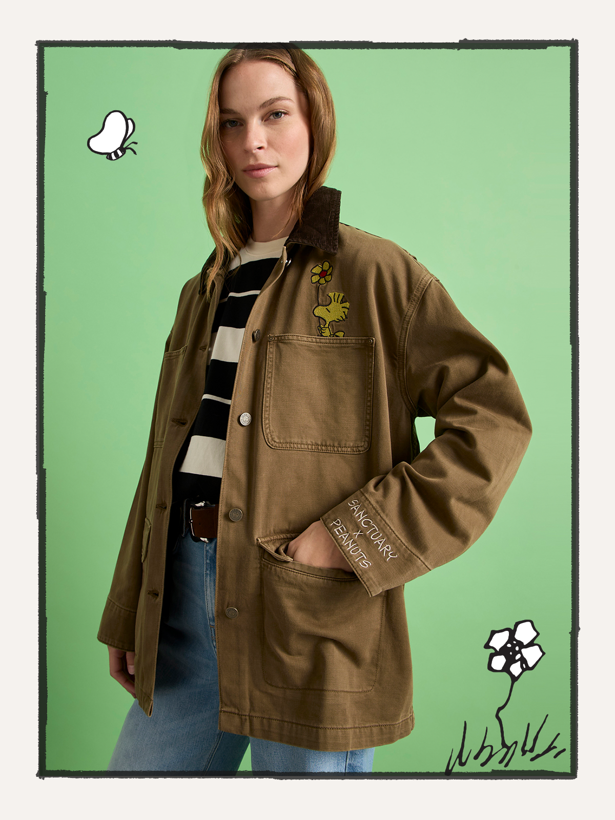 A woman stands against a green background wearing Sanctuary Clothing's "save our planet jacket timber," featuring cartoon patches, paired with a black and white striped shirt and blue jeans. Hand-drawn doodles decorate the image's border.