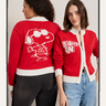 Two women wear Sanctuary Clothing "joe cool zip up sweater cherry lacquer" cardigans—one with Snoopy and "Joe Cool" on the back, the other with a "RIGHT ON" patch on the front. They stand side by side, facing opposite directions.