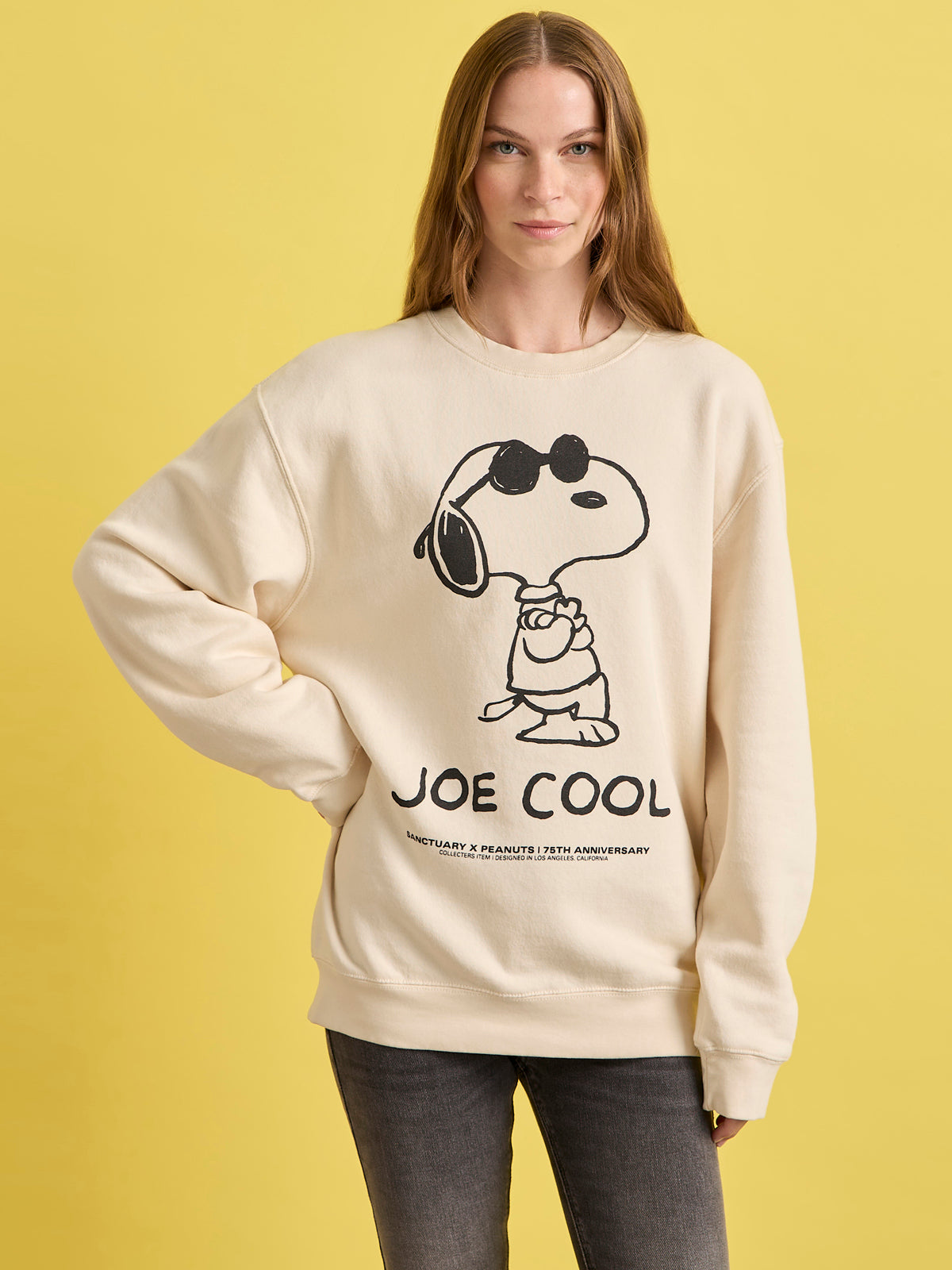Person wearing a beige sweatshirt with a graphic of Snoopy and 'Joe Cool' text on a yellow background