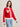 A woman in the Sanctuary Clothing x PEANUTS 75th Anniversary joe cool zip up sweater cherry lacquer, featuring white collar, cuffs, hem, and bold "RIGHT ON" text. She has shoulder-length brown hair and light blue jeans.