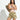 A woman with long dark hair stands confidently with arms crossed, wearing Sanctuary Clothing's wander on short canyon camo shorts and a light pink tank top, carrying a brown shoulder bag against a plain white background.
